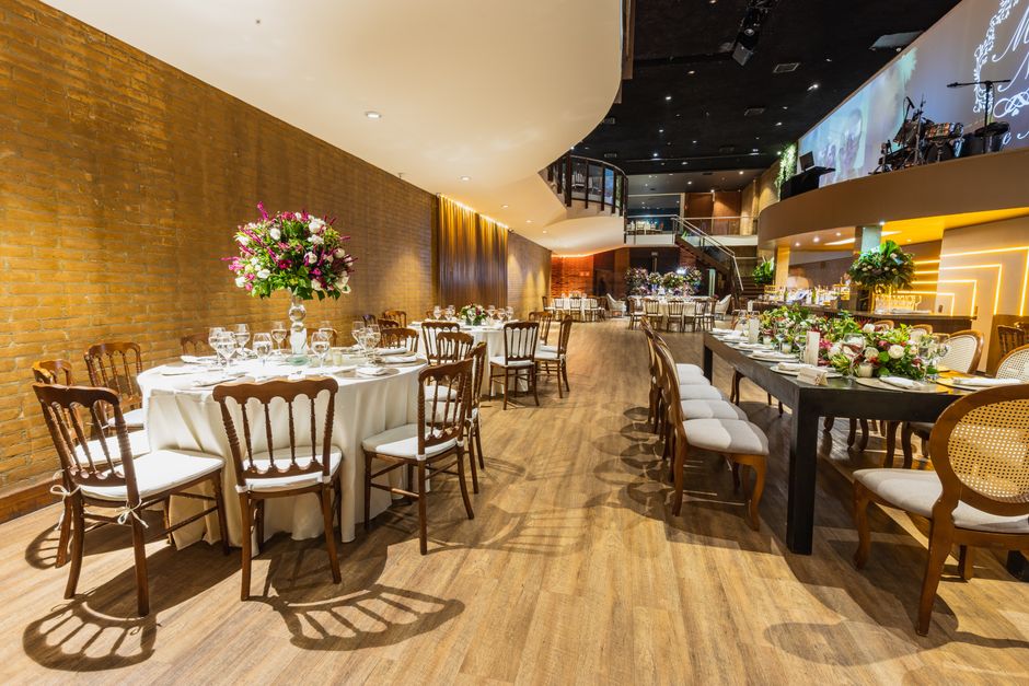 Salão de eventos decorado com mesas e cadeiras para celebração, com foco na ambientação elegante e acolhedora para festas e encontros sociais.