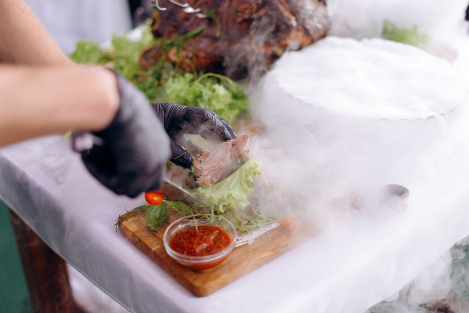 Imagem de um chef preparando um prato sofisticado de gastronomia contemporânea, com uso de técnicas de fumaça e decoração com vegetais frescos.