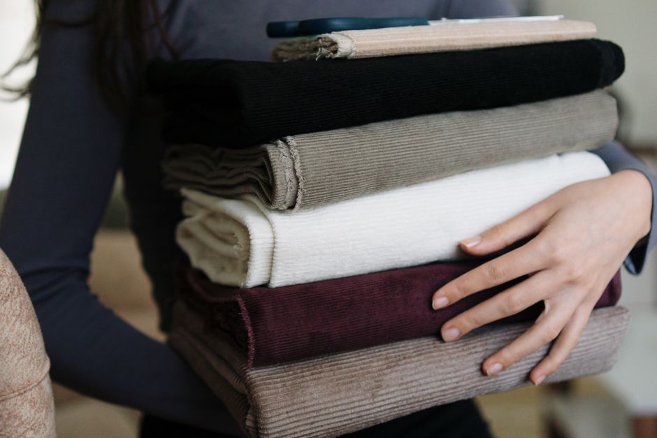 Imagem de uma pessoa carregando uma pilha de roupas organizadas, ideal para ilustrar organização e rotina doméstica em blog de dicas de arrumação.
