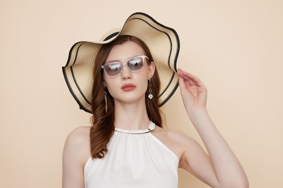 Mulher estilosa usando chapéu de verão e óculos de sol, transmitindo elegância e clima de lazer.