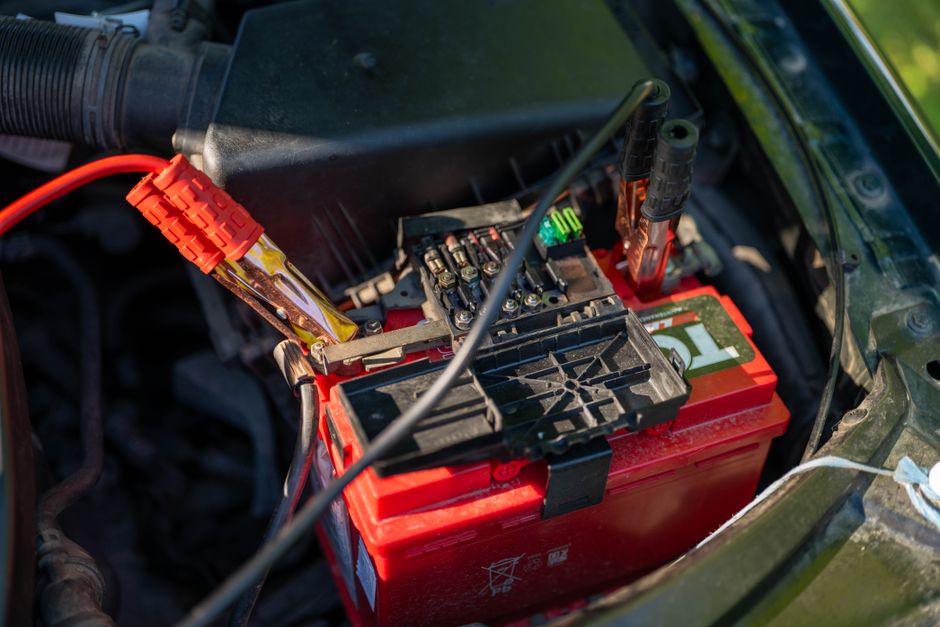 Imagem de uma bateria de carro sendo carregada ou revisada, indicando manutenção automotiva ou problemas elétricos no veículo.