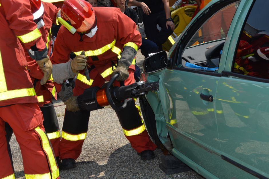 Bombeiro utilizando ferramenta de resgate para cortar um carro, demonstrando esforços de emergência e salvamento em acidentes.