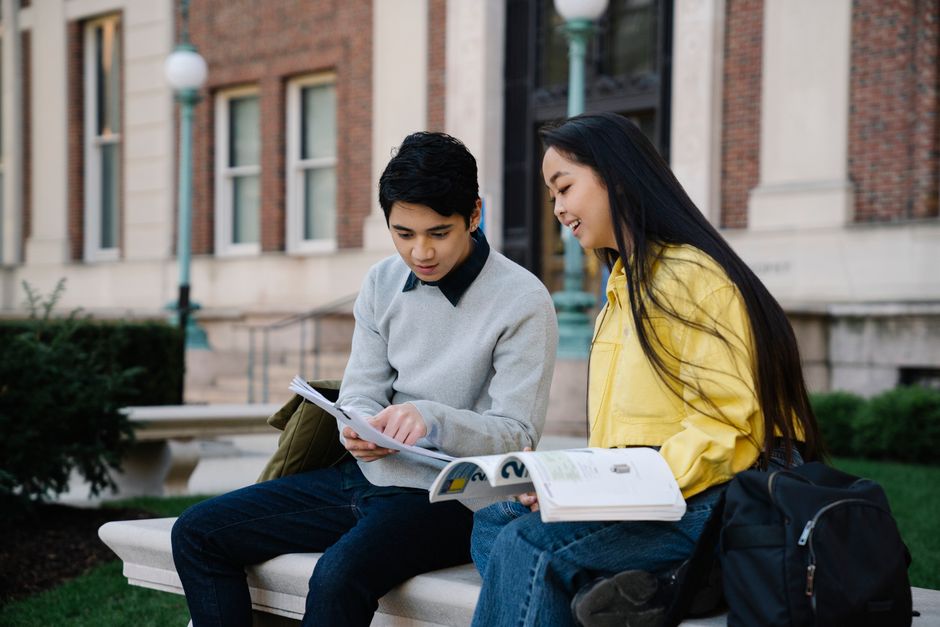 Jovens estudantes conversando e trocando estudos em parque universitário ao ar livre.