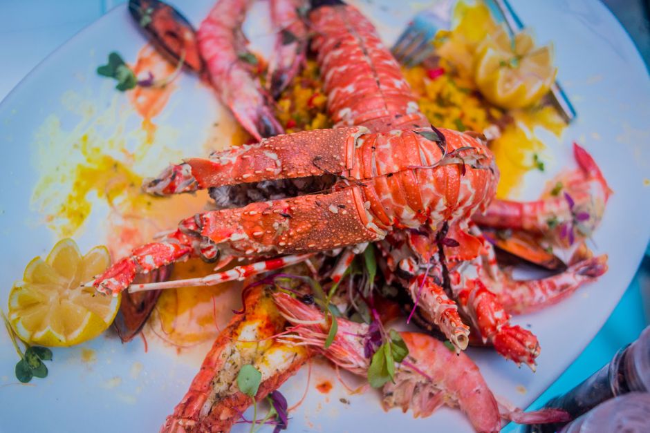 Imagem de uma porção de lagostas e camarões servidos com acompanhamentos cítricos, ideal para ilustrar gastronomia marítima ou pratos de frutos do mar para blog de culinária.