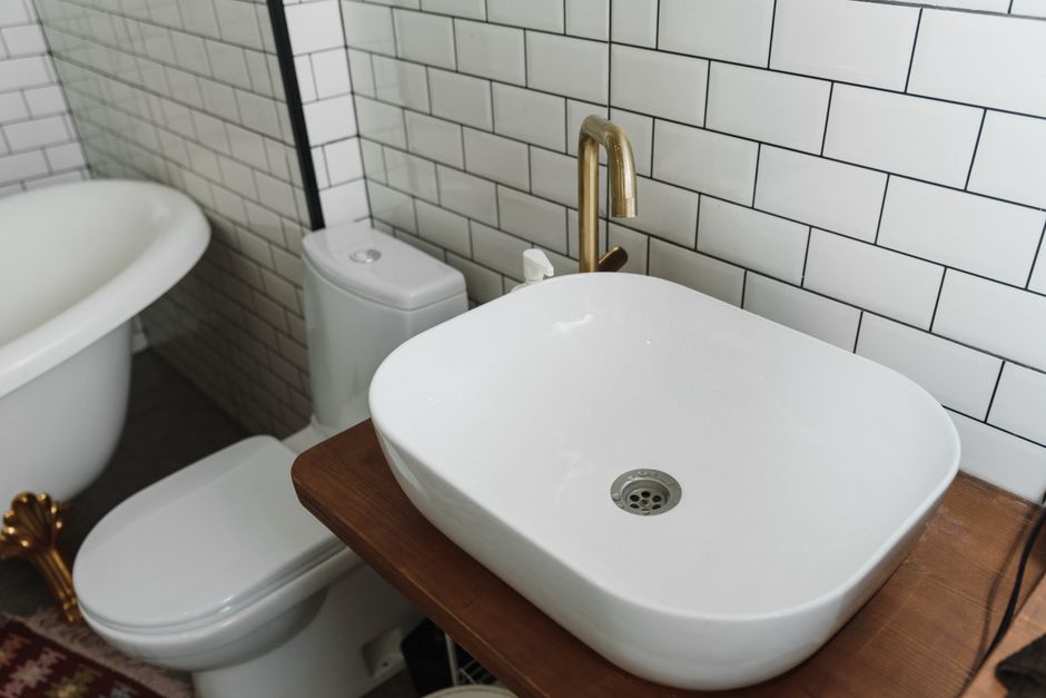 Imagem de banheiro com pia, vaso sanitário e banheira, destacando o estilo minimalista e a combinação de elementos clássicos e modernos.