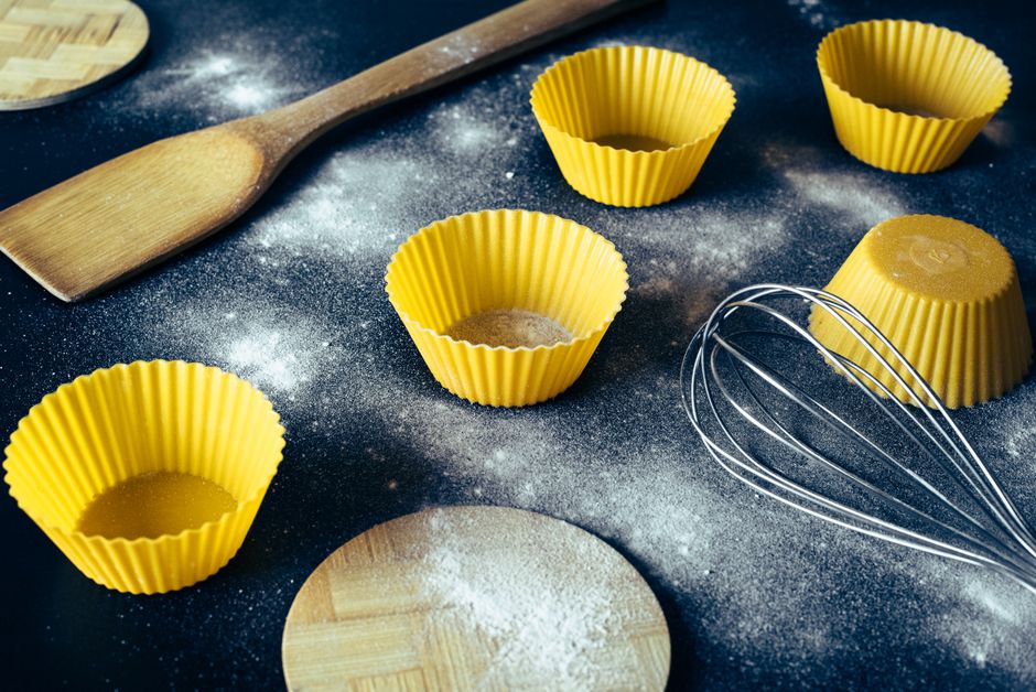 Imagem de utensílios de cozinha e forminhas de papel utilizadas na preparação de massas ou sobremesas, destacando um ambiente de gastronomia caseira ou culinária artesanal.