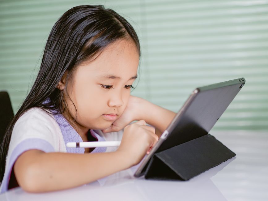 Garota estudando ou usando um tablet, representando aprendizagem e tecnologia infantil.