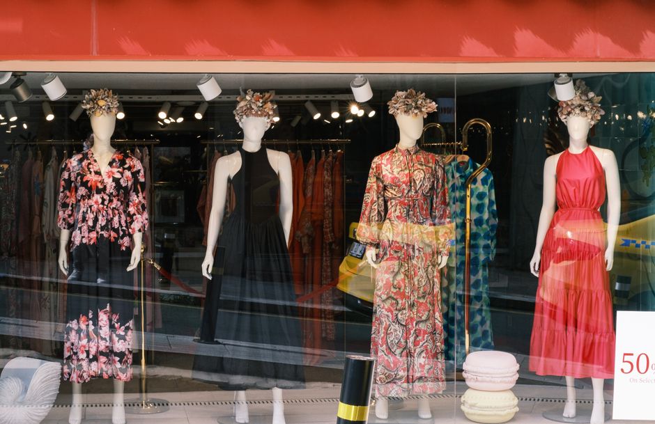 Vitrine de loja de roupas femininas exibindo vestidos elegantes e acessórios de moda em um ambiente de comércio varejista.