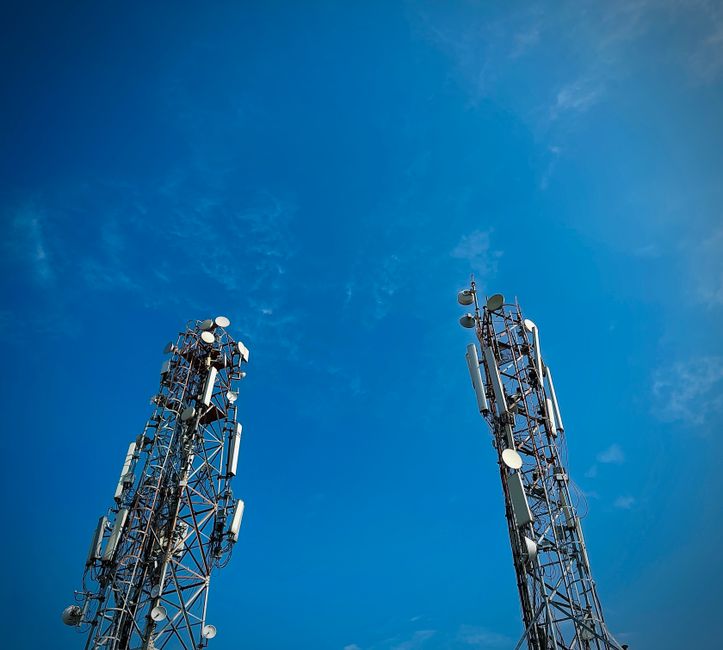 Imagem mostrando torres de comunicação sob um céu azul, simbolizando tecnologia e conectividade.
