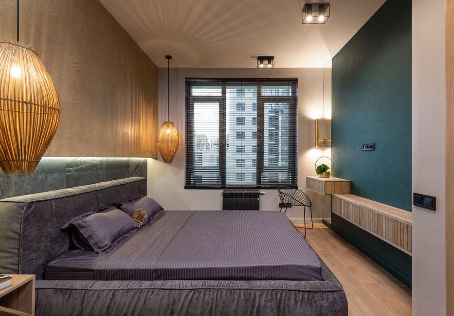 Quarto moderno com decoração aconchegante, elementos de iluminação e janelas com vista urbana, ideal para uso em artigos sobre decoração e design de interiores.