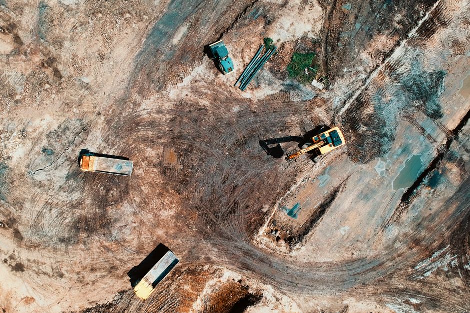 Imagem aérea de um canteiro de obras com máquinas e equipamentos de construção, representando progresso na obra civil.