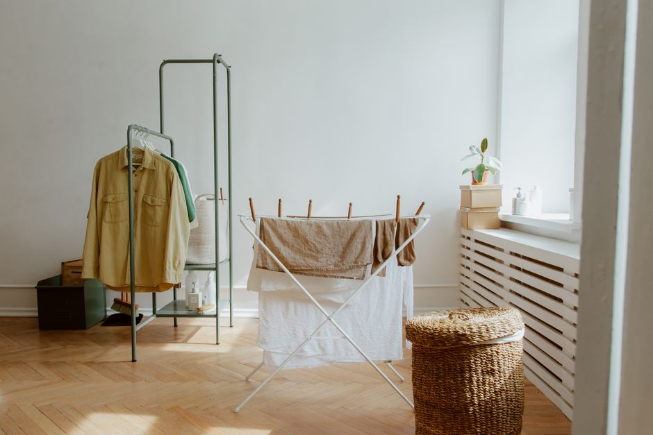 Espaço de lavanderia residencial com roupas penduradas para secar e ambiente organizado e arejado.