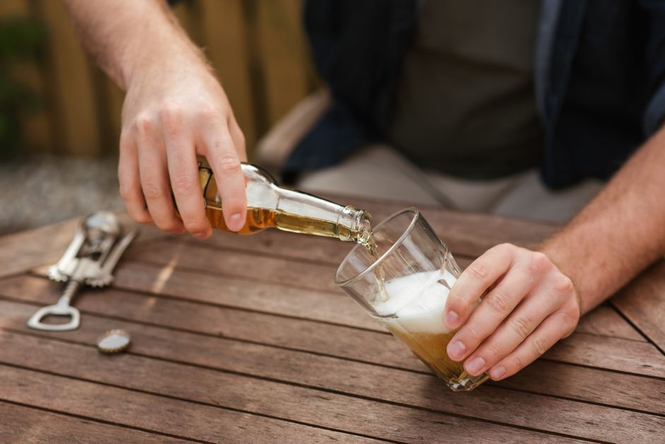 Homem servindo cerveja em um ambiente externo, destacando momentos de lazer e descontração.