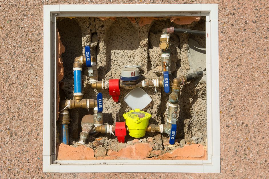 imagem de uma instalação de encanamentos de água embutida na parede, mostrando conexões, registros e tubulações expostas em uma obra ou manutenção residencial