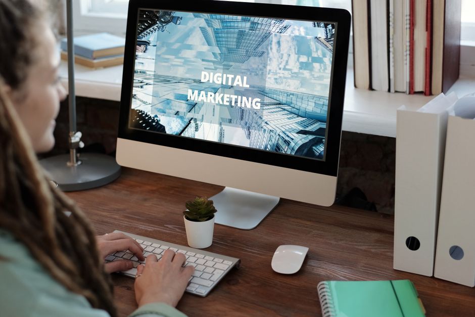 Pessoa trabalhando em um computador com foco em marketing digital, em um ambiente de escritório bem iluminado.