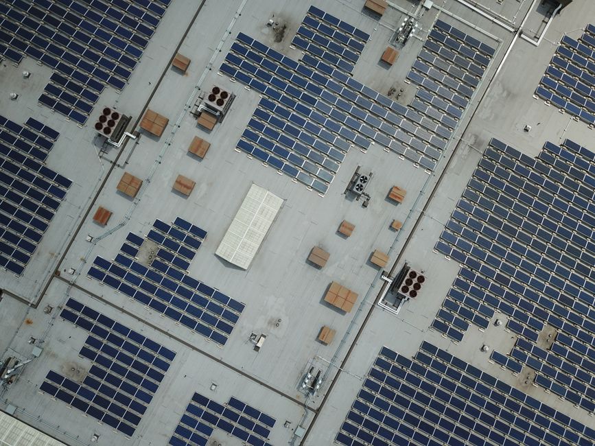 Imagem de uma cobertura de edifício com uma vasta instalação de painéis solares, destacando o uso de energia renovável em ambientes urbanos.