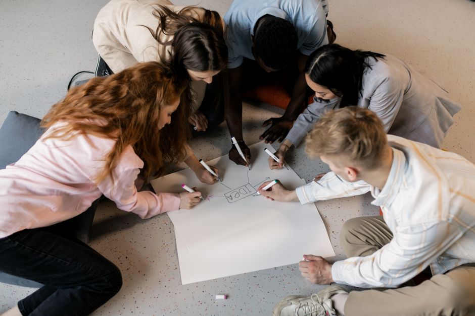 Grupo de jovens colaborando em projeto criativo, simbolizando trabalho em equipe e inovação.