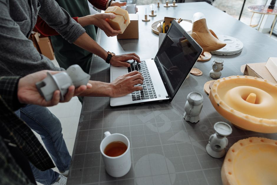 Pessoas trabalhando em um ambiente de escritório com um laptop, compartilhando ideias e consumindo queijos artesanais, demonstrando criatividade e colaboração.