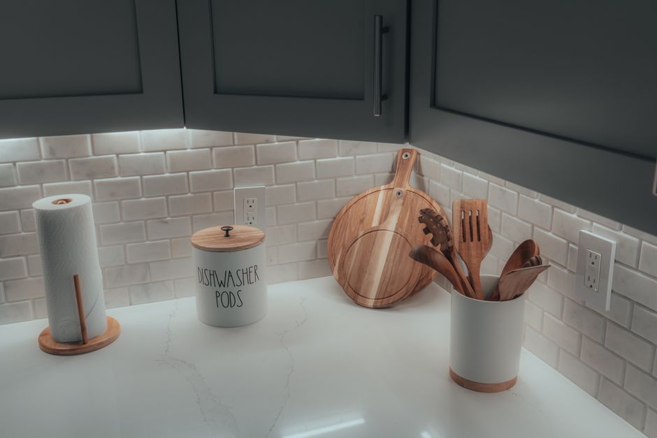 Imagem de uma área de cozinha bem organizada com utensílios de madeira e dispensador de papel-toalha, ideal para ilustrar organização doméstica ou decoração minimalista.