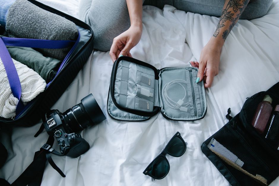 Pessoa organizando equipamentos de fotografia em um ambiente interno, preparando-se para uma viagem ou ensaio fotográfico.