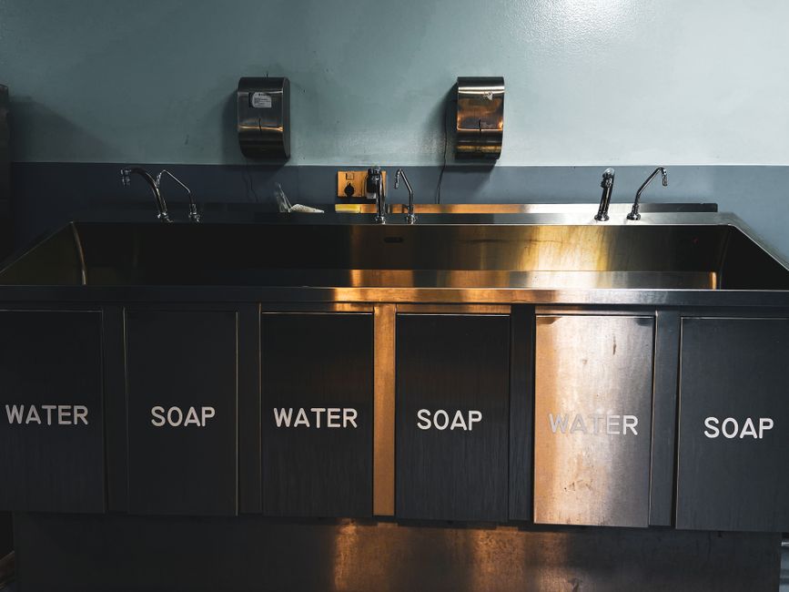 Imagem de uma pia com torneiras em um espaço que parece ser uma área de higiene ou preparação, com destaque para a funcionalidade do ambiente.