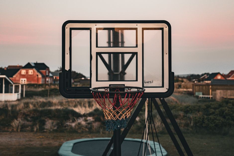 Imagem de uma cesta de basquete ao entardecer, simbolizando esportes, lazer e atividade física ao ar livre.