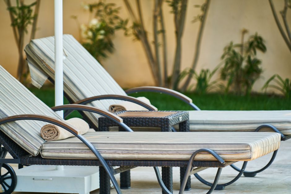 Duas espreguiçadeiras de piscina com detalhes de toalhas e um ambiente ao ar livre perfeito para relaxar e aproveitar o verão.