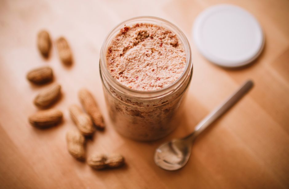 Imagem de um pote de suplemento de proteína com amendoins ao lado, ideal para um artigo sobre nutrição esportiva ou alimentação saudável.