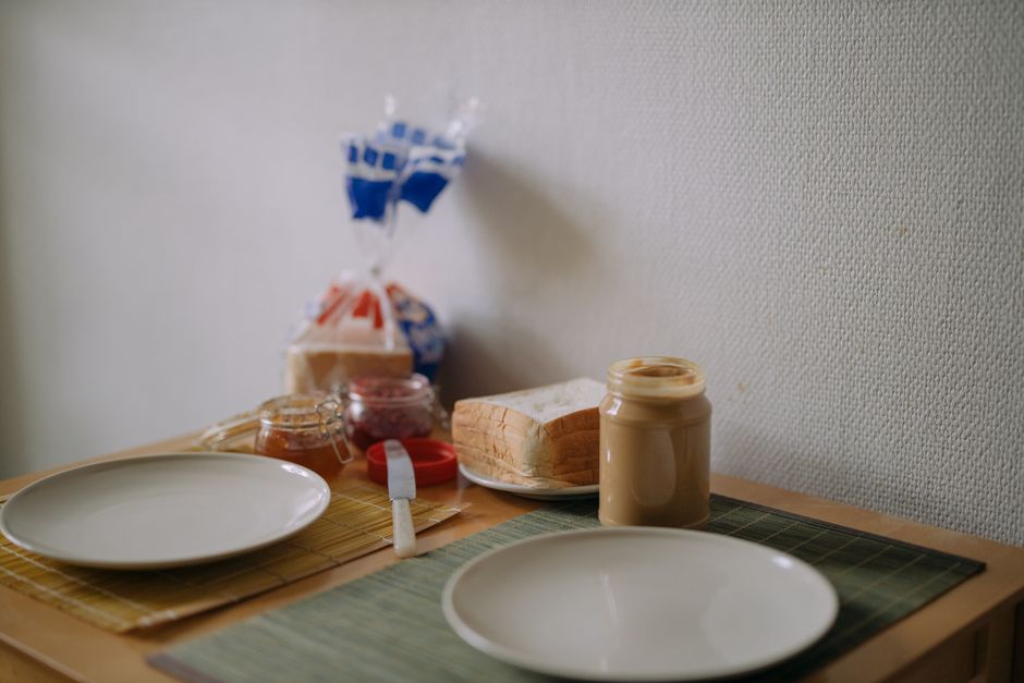 Mesa de café da manhã com pão, geleias e manteiga, sugerindo um momento de alimentação e rotina diária.