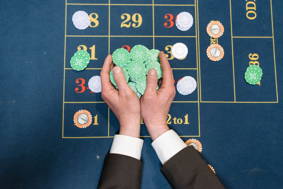 Pessoa jogando dados em uma mesa de cassino, representando sorte ou jogos de azar.