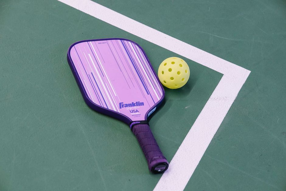 Raquete de tênis e bola posicionadas em quadra, simbolizando esporte e prática física.