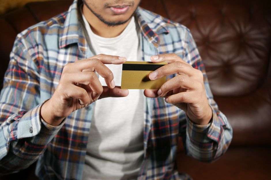 Homem usando cartão de crédito em um ambiente acolhedor, ilustrando temas de finanças pessoais ou compras online.