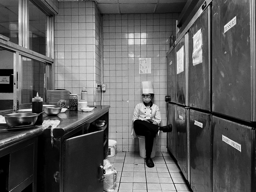 Chef de cozinha descansando em uma cozinha comercial, refletindo sobre o processo de preparação de alimentos.