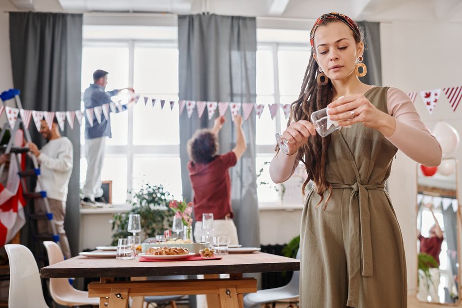 Mulher arrumando a decoração em uma festa familiar, com crianças e adultos preparando o ambiente.
