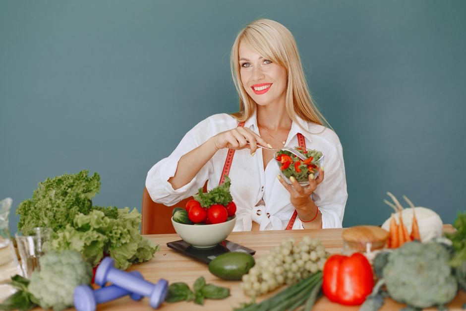 Mulher sorridente preparando uma salada saudável em um ambiente de cozinha, promovendo bem-estar e alimentação equilibrada.