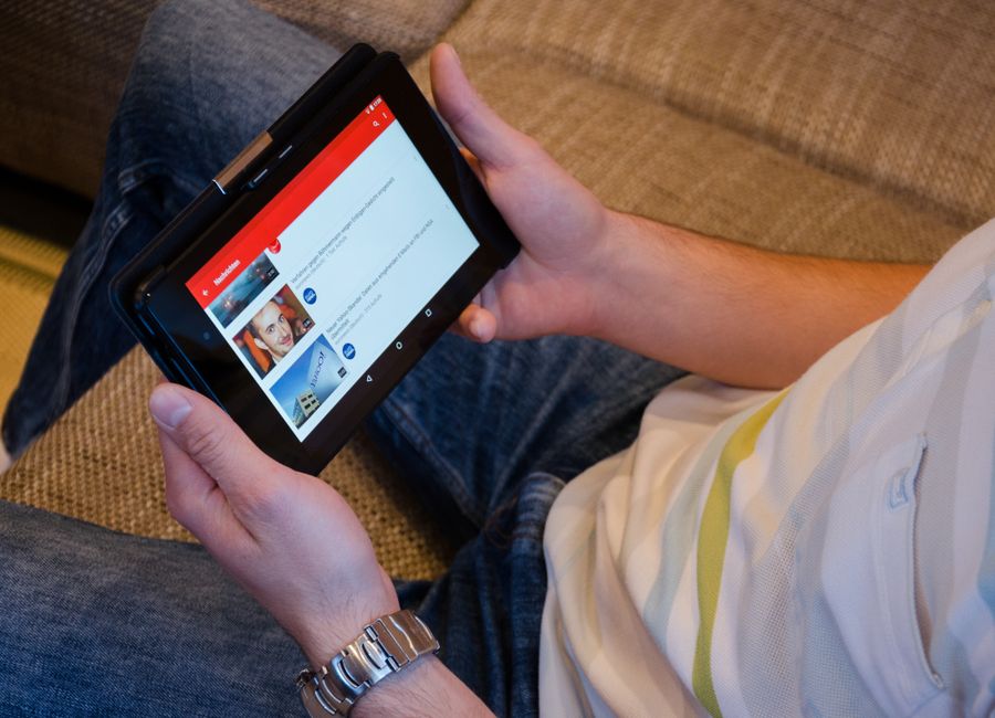 Pessoa assistindo vídeos no tablet, representando entretenimento digital ou conteúdo online em um ambiente descontraído.