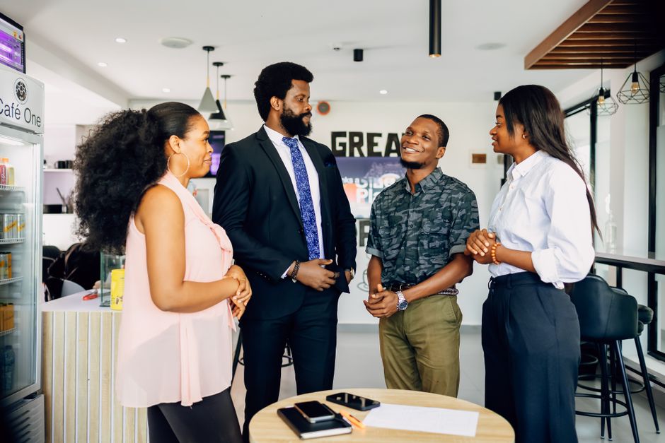 Grupo de profissionais em uma conversa informal em ambiente de coworking ou reunião de negócios, refletindo networking e colaboração empresarial.