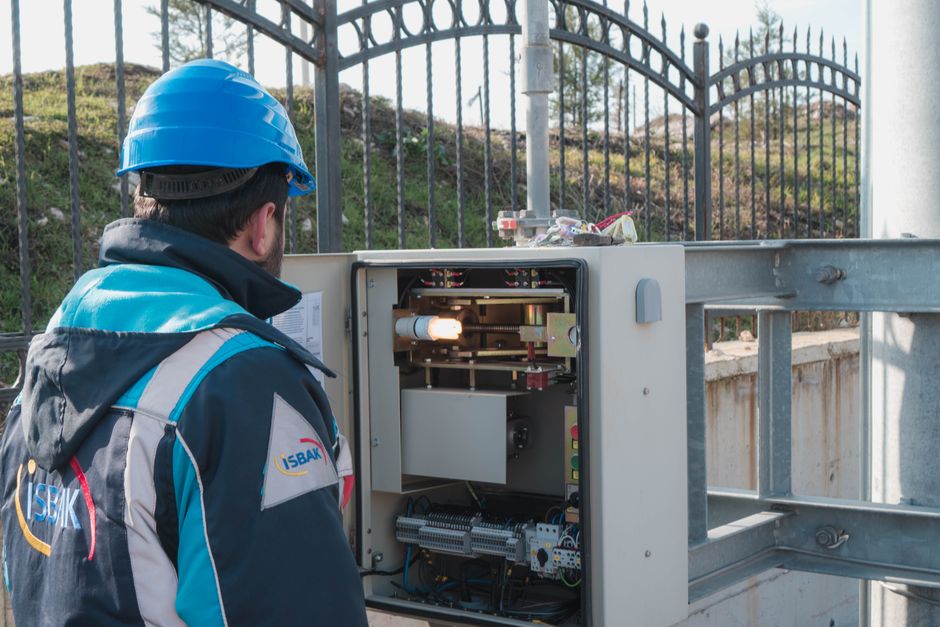 Técnico em manutenção de infraestrutura de energia elétrica ao inspecionar equipamento em campo ao ar livre