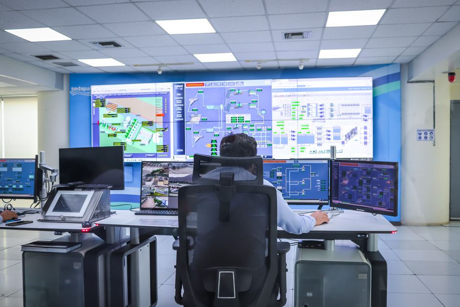 Profissional monitorando sistemas automatizados em um centro de controle de operações industriais.