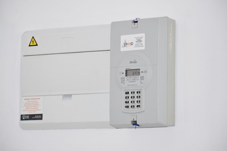 Sistema de gerenciamento de energia elétrica instalado na parede de uma sala corporativa, representando controle e eficiência energética.