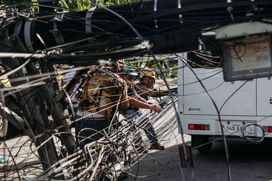 Homens trabalharam em uma instalação de infraestrutura elétrica ao ar livre, com foco na manutenção de cabos e fios.