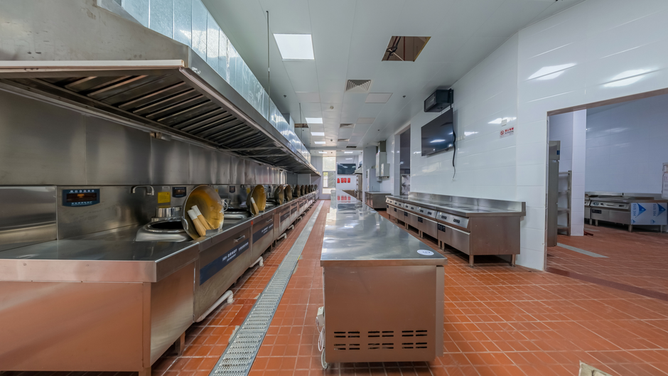 Imagem de uma cozinha industrial moderna, com equipamentos de preparo de alimentos e ambiente limpo e organizado, utilizada como ilustração de processos de cozinha profissional ou segurança alimentar.