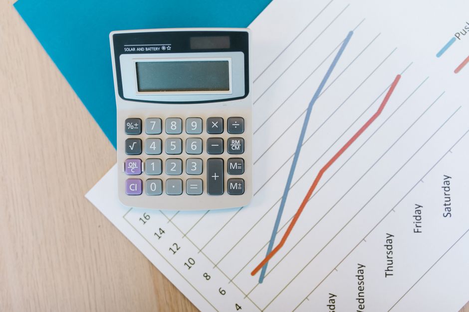 Imagem de uma calculadora sobre gráficos de desempenho financeiro, simbolizando análise de resultados e planejamento financeiro.