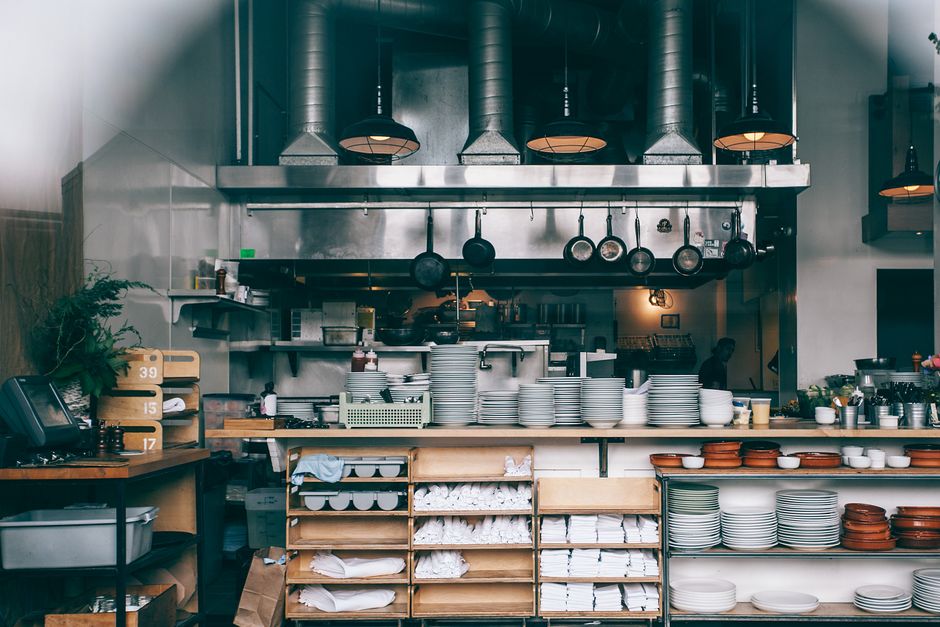 Ambiente de cozinha de restaurante com utensílios e pratos organizados, pronto para o preparo de refeições.