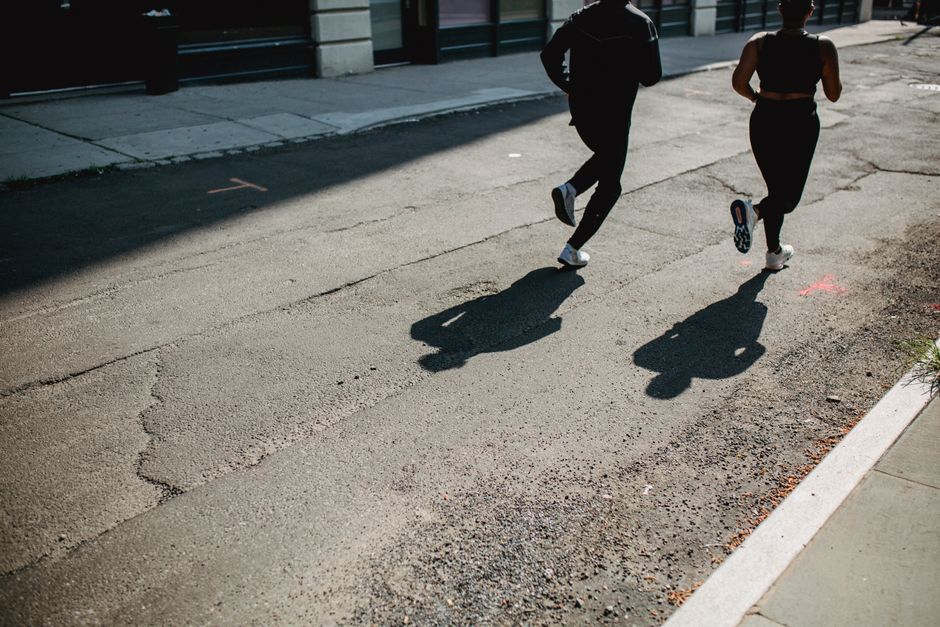 Dupla de pessoas correndo à tarde em uma rua urbana, simbolizando saúde, bem-estar ou rotina de exercícios ao ar livre.