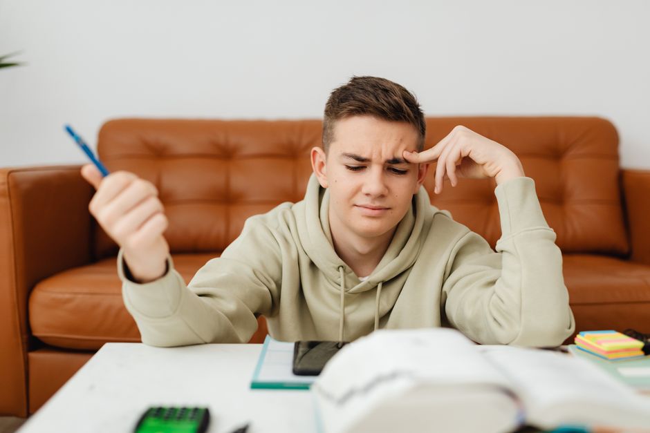 Jovem estudando e tentando resolver um problema complexo, refletindo sobre dificuldades acadêmicas ou pessoais.