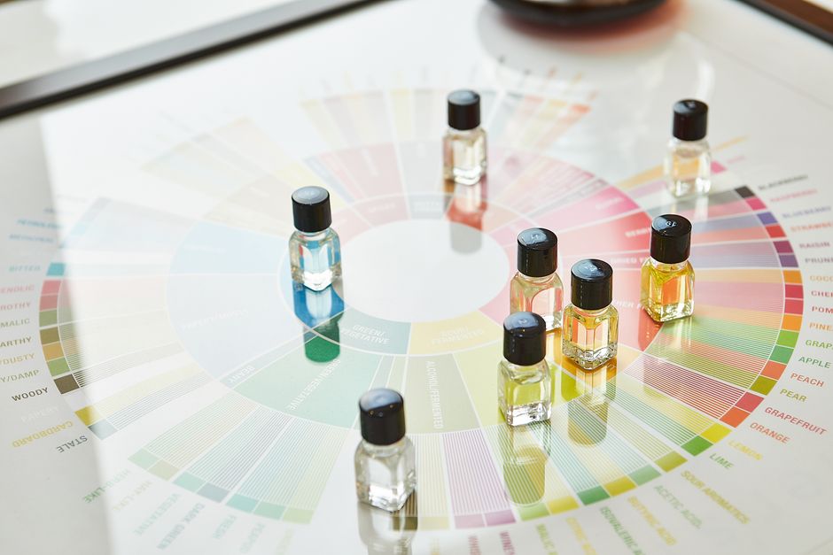 Imagem de frascos de óleos essenciais sobre uma tabela colorida de referências de cores, sugerindo temas de aromaterapia, bem-estar ou terapias naturais.