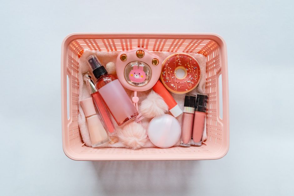 Caixa de armazenamento com produtos de beleza e cuidados pessoais em tons rosa e decorativos, ideal para um artigo sobre organização de cosméticos e cuidados de beleza.
