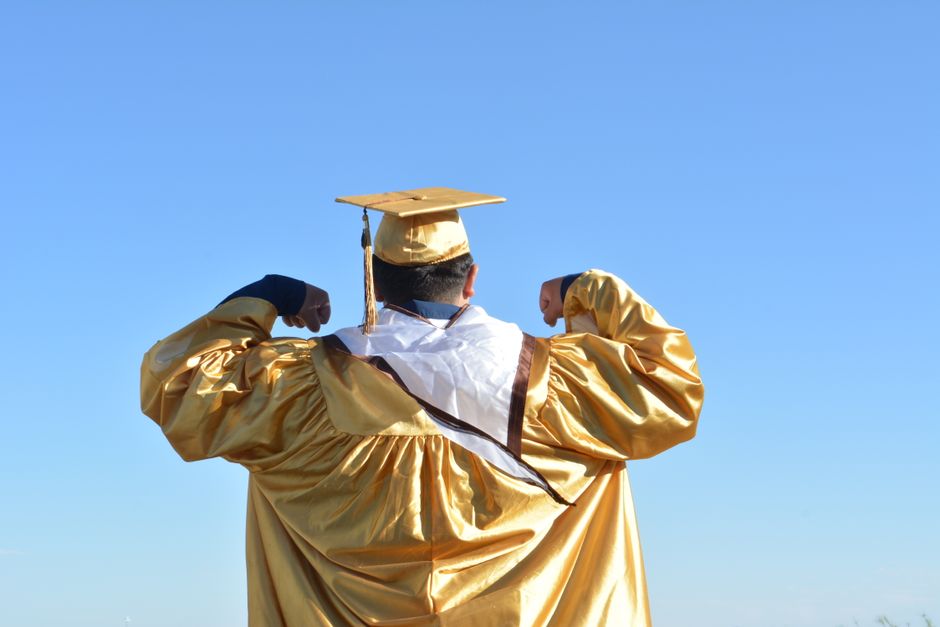 Estudante de graduação comemorando a conquista do diploma ao ar livre, simbolizando realização acadêmica.