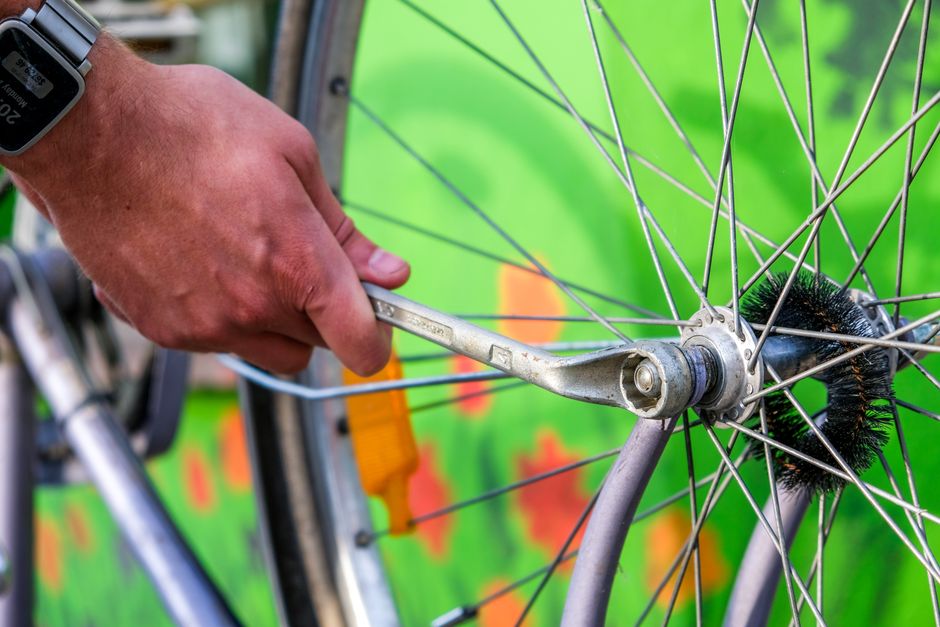 Pessoa consertando uma roda de bicicleta, destacando a manutenção e o cuidado com o equipamento.